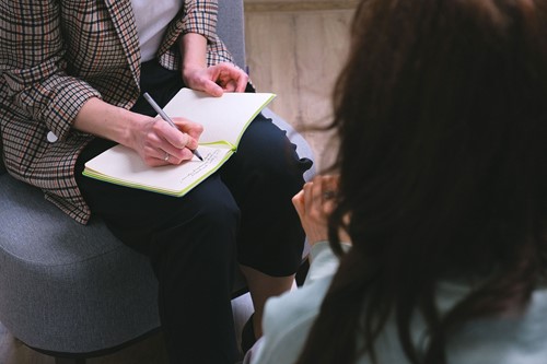 An adviser making notes in a notebook during a conversation