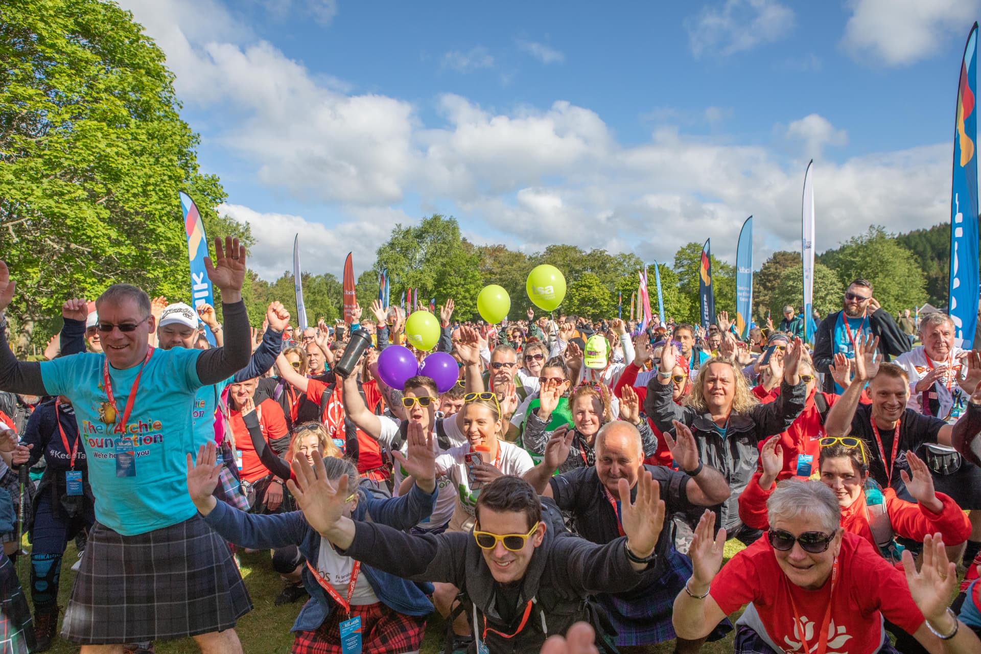 Crowd of Kiltwalk fundraisers cheering with hands in the air