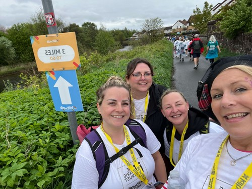 Four Team Marie Trust walkers smiling beside a three miles to go sign