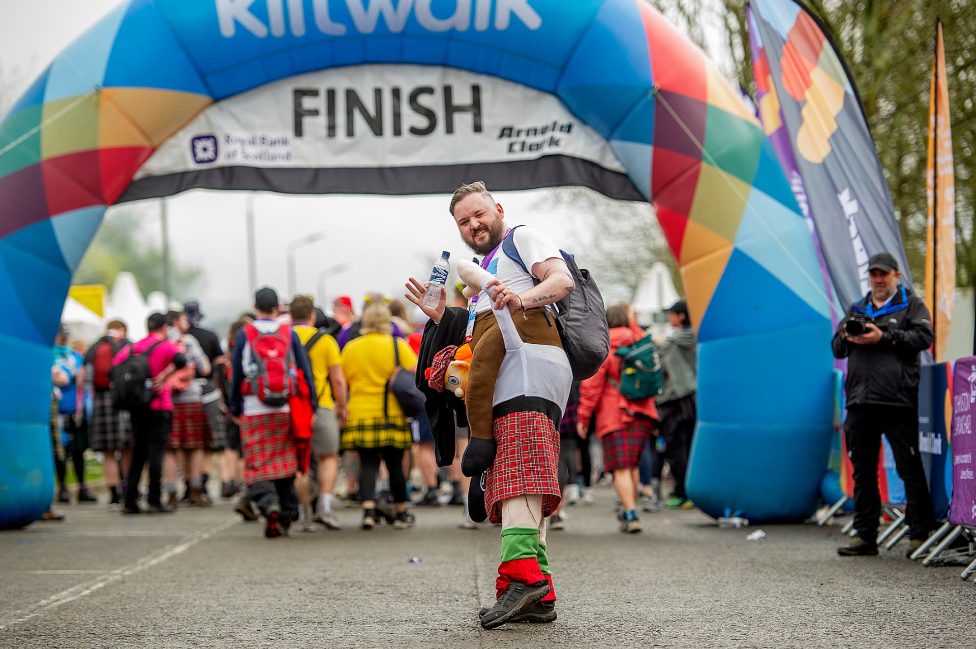 Kiltwalker in a tartan kilt celebrating at the Kiltwalk finish arch