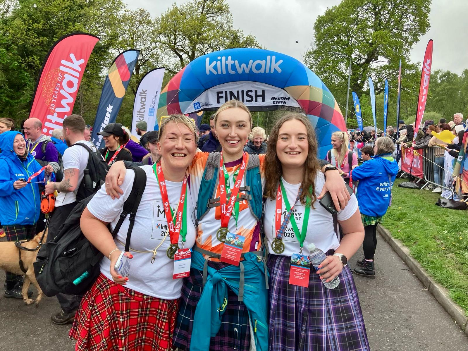 Three supporters in Marie Trust t-shirts at the Kiltwalk finish line